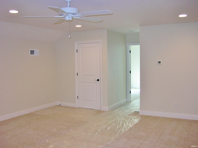 empty room featuring light carpet, vaulted ceiling, and ceiling fan