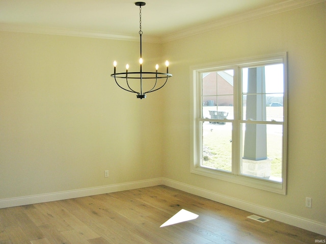 unfurnished dining area featuring a healthy amount of sunlight, light wood-type flooring, ornamental molding, and a notable chandelier