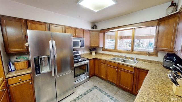 kitchen with light tile flooring, appliances with stainless steel finishes, light stone countertops, and sink