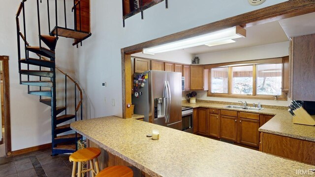 kitchen with appliances with stainless steel finishes, a breakfast bar, sink, kitchen peninsula, and dark tile floors