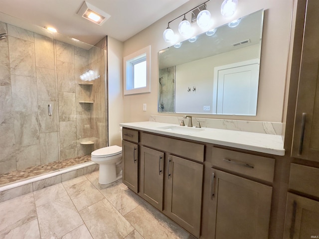 bathroom featuring tile floors, toilet, a shower with shower door, and vanity with extensive cabinet space