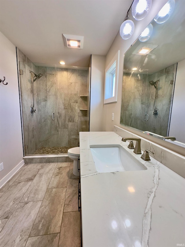 bathroom featuring tile flooring, a shower with door, toilet, and vanity with extensive cabinet space