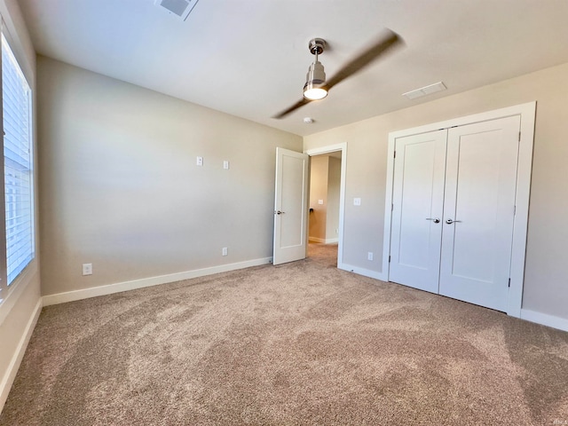 unfurnished bedroom featuring a closet, light colored carpet, ceiling fan, and multiple windows