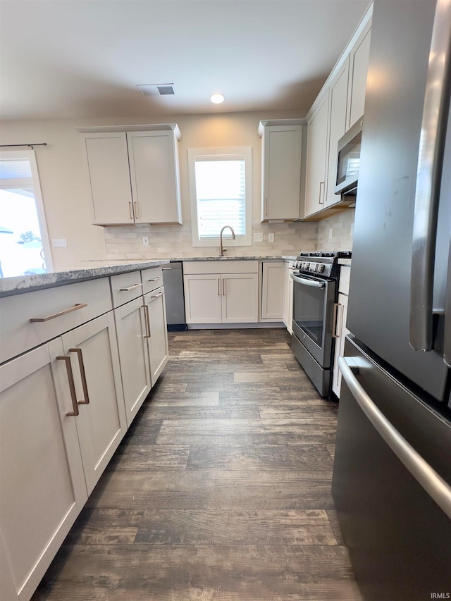 kitchen featuring tasteful backsplash, stainless steel appliances, dark hardwood / wood-style floors, and light stone counters