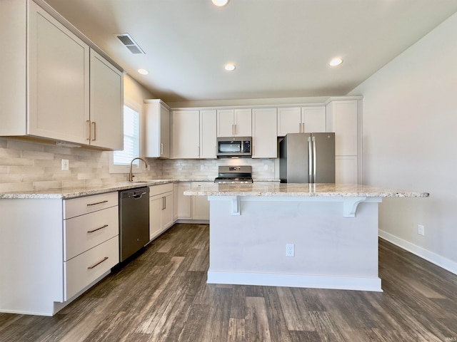 kitchen featuring a kitchen breakfast bar, a kitchen island, dark hardwood / wood-style floors, and stainless steel appliances