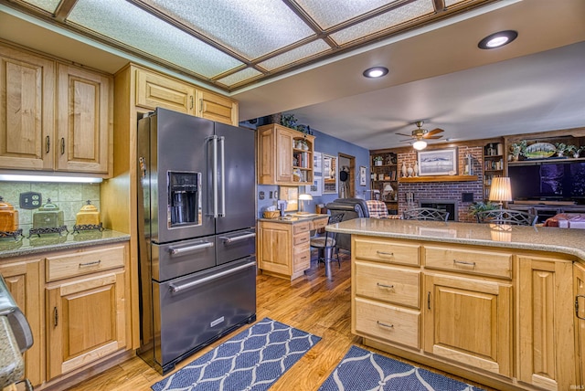 kitchen featuring light hardwood / wood-style floors, a fireplace, ceiling fan, tasteful backsplash, and high end refrigerator