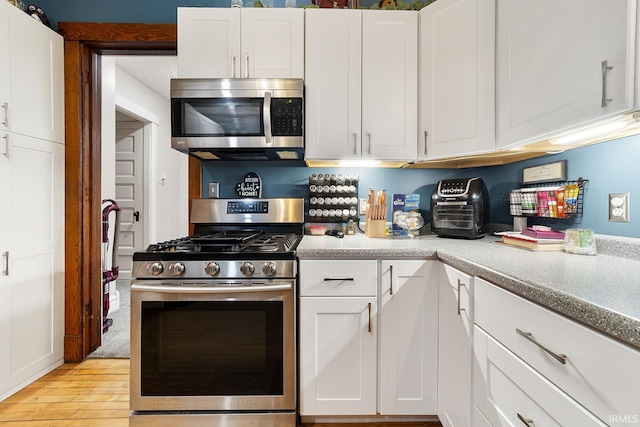 kitchen featuring white cabinets, appliances with stainless steel finishes, and light hardwood / wood-style flooring