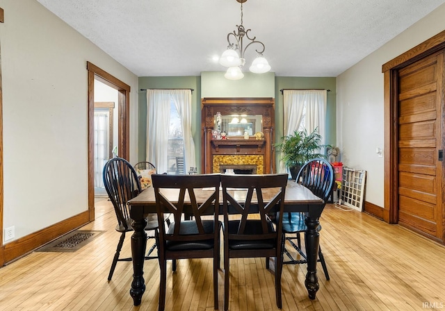 dining space with a chandelier, light hardwood / wood-style flooring, and a textured ceiling