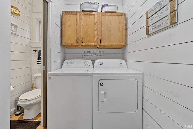 laundry area featuring wood walls, washing machine and dryer, and hardwood / wood-style flooring