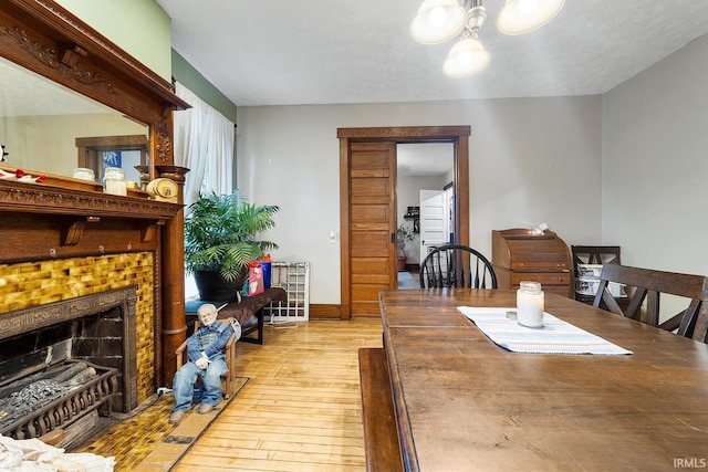 dining area featuring a tile fireplace and light wood-type flooring