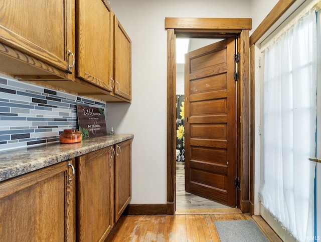 kitchen featuring stone counters, backsplash, and light wood-type flooring