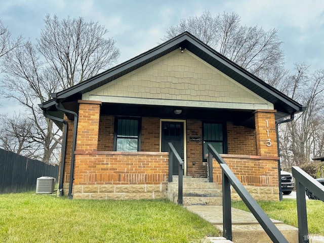 bungalow-style home featuring covered porch, a front yard, and central air condition unit