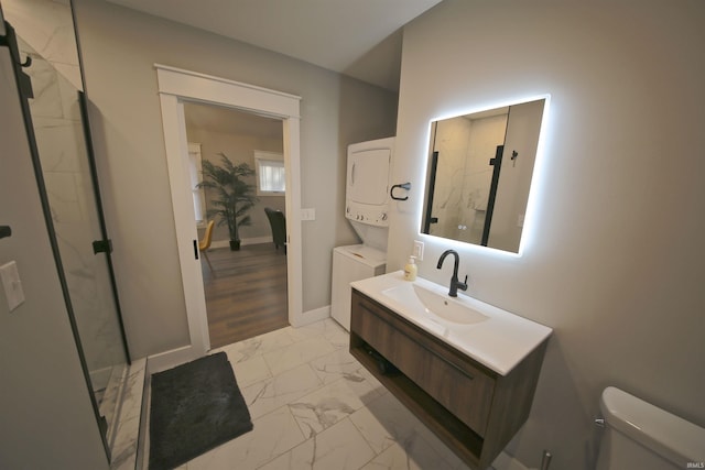 bathroom with toilet, a shower with door, tile floors, stacked washer and clothes dryer, and oversized vanity