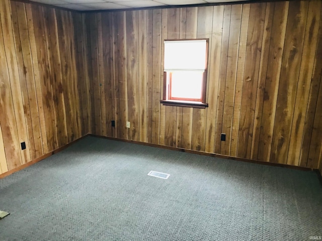 carpeted spare room with wood walls