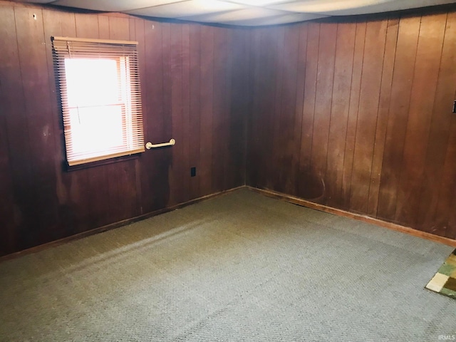 spare room featuring wood walls and dark colored carpet