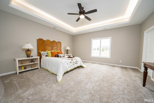 carpeted bedroom with a tray ceiling, baseboards, and ceiling fan