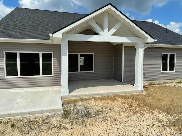 back of property with a patio and a shingled roof