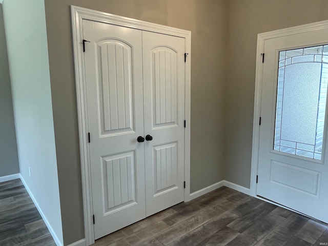 foyer featuring baseboards and dark wood-style floors