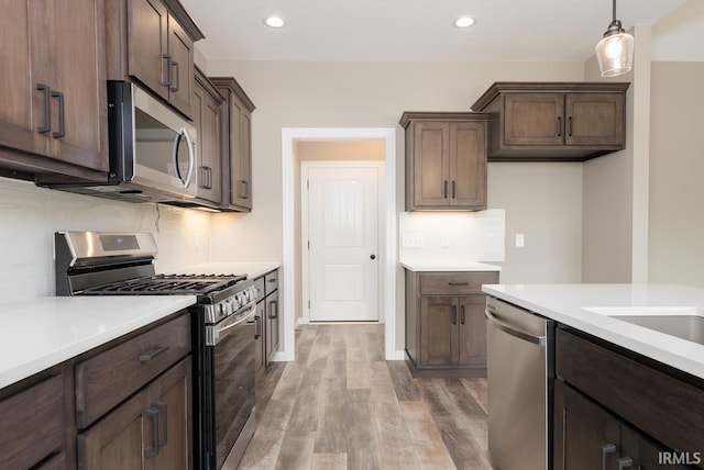 kitchen with light countertops, light wood-type flooring, dark brown cabinetry, and stainless steel appliances