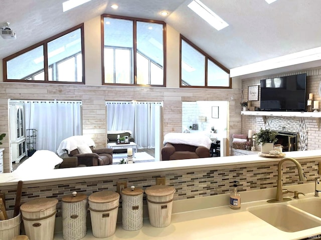 interior space with high vaulted ceiling, sink, a skylight, and a wealth of natural light