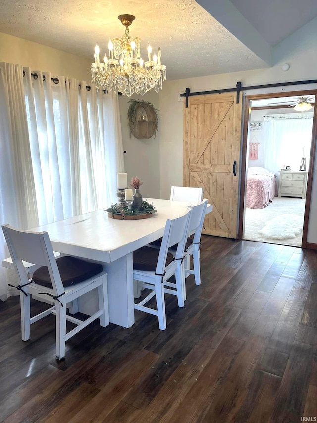 dining room featuring a barn door, a notable chandelier, a textured ceiling, and dark wood-type flooring