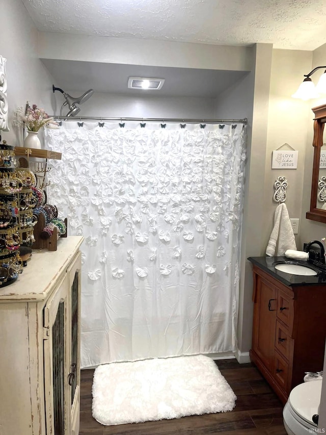 bathroom featuring toilet, a textured ceiling, vanity, and hardwood / wood-style flooring