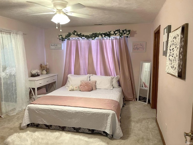 bedroom featuring light carpet, a textured ceiling, and ceiling fan