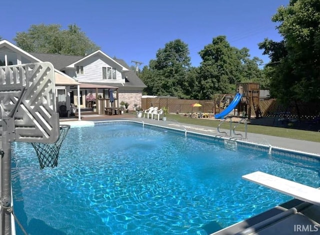 view of pool with a playground, a patio, and a diving board