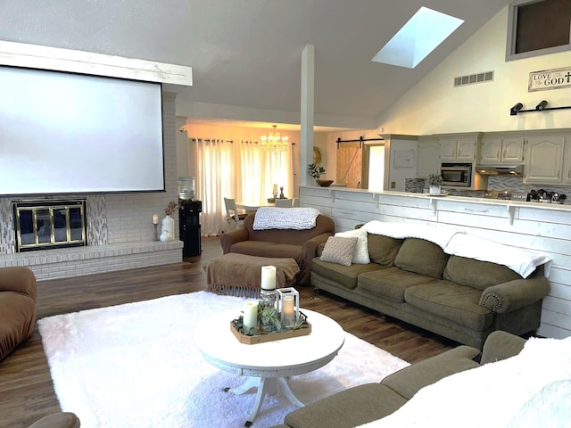 living room with a notable chandelier, a skylight, dark hardwood / wood-style flooring, and a fireplace