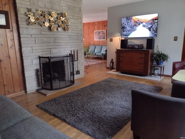 living room with a fireplace, brick wall, light wood-type flooring, and wooden walls