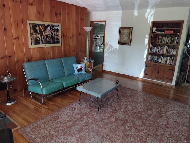 living room featuring built in features, wood walls, and dark hardwood / wood-style flooring