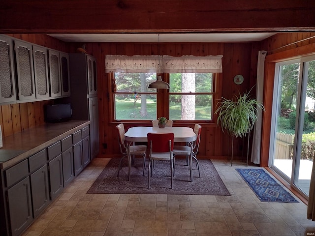 tiled dining area featuring plenty of natural light and wood walls