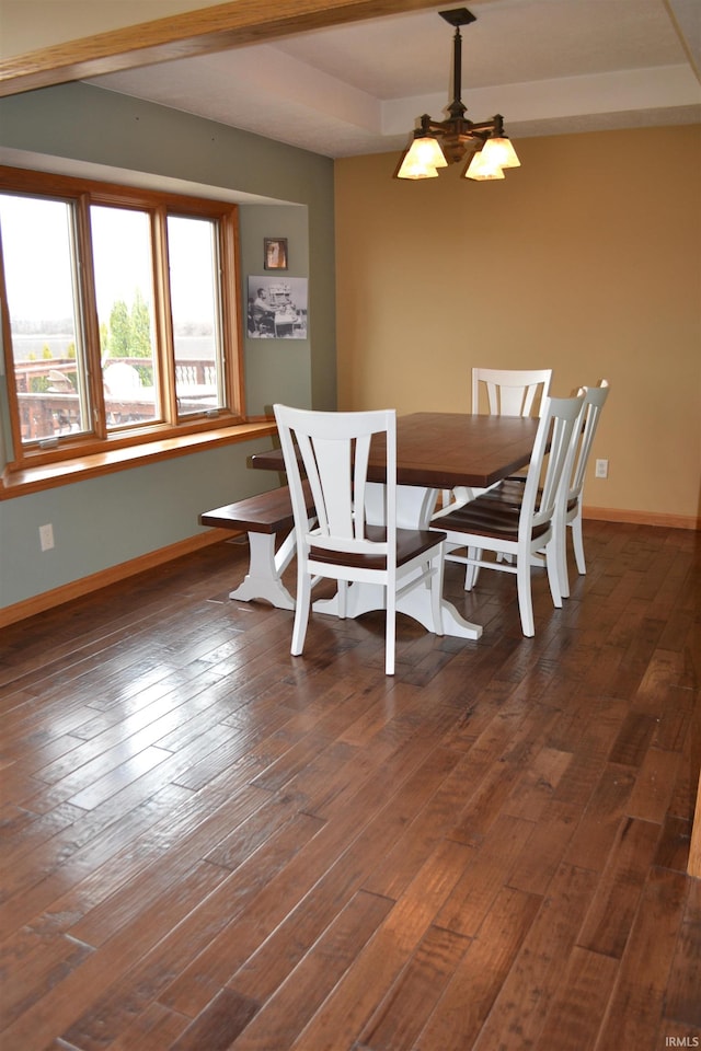 dining room with a raised ceiling, a notable chandelier, and dark hardwood / wood-style floors