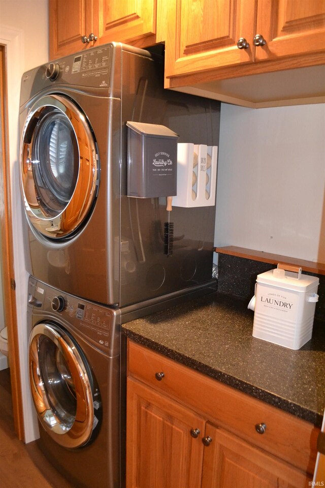 laundry room featuring cabinets and stacked washer and clothes dryer