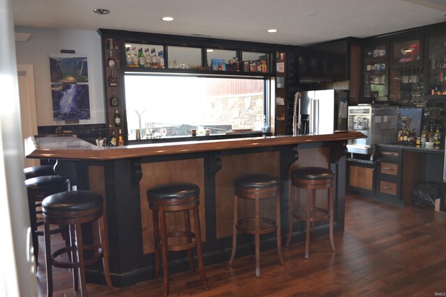 bar with dark wood-type flooring and high quality fridge