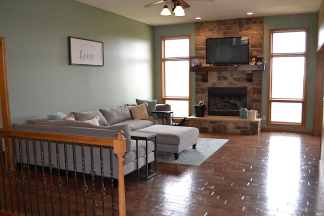 living room with a stone fireplace, dark hardwood / wood-style floors, and ceiling fan