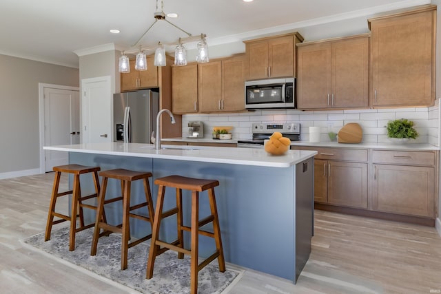 kitchen featuring sink, appliances with stainless steel finishes, light wood-type flooring, and an island with sink