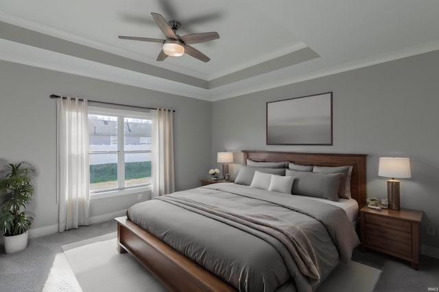 carpeted bedroom featuring ornamental molding, a tray ceiling, and ceiling fan