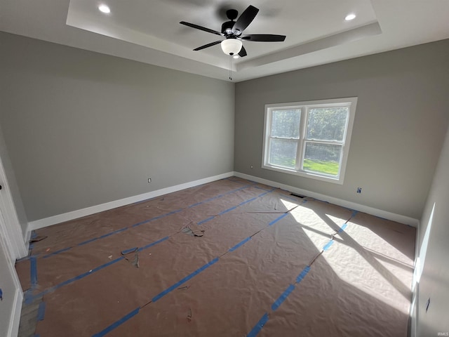 unfurnished room with ceiling fan and a raised ceiling