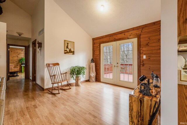 doorway featuring wooden walls, light wood-type flooring, and french doors