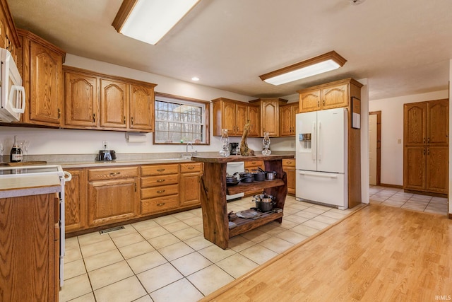 kitchen with white appliances, sink, and light tile floors