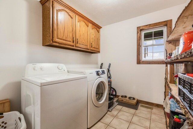 washroom with cabinets, washing machine and clothes dryer, and light tile flooring