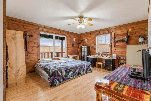 bedroom with wood walls, ceiling fan, and light hardwood / wood-style flooring