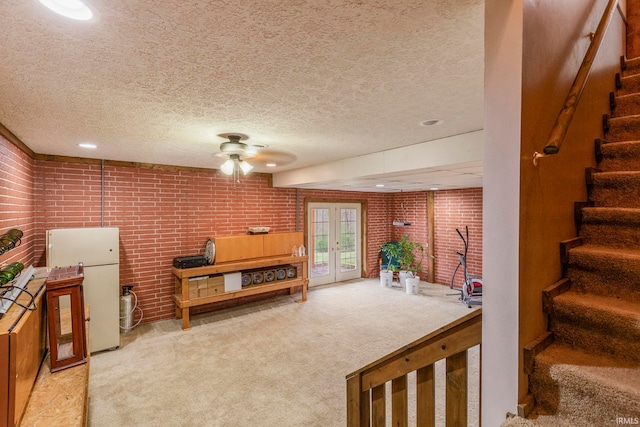 living room featuring light colored carpet, french doors, brick wall, ceiling fan, and a textured ceiling