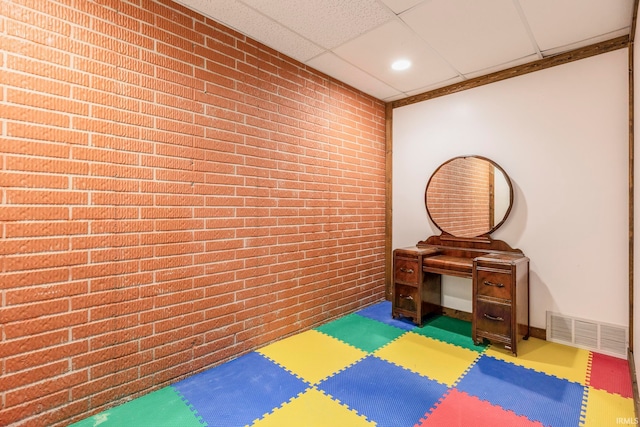 exercise area featuring a drop ceiling and brick wall