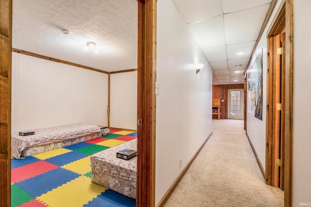 hall with a paneled ceiling and light colored carpet