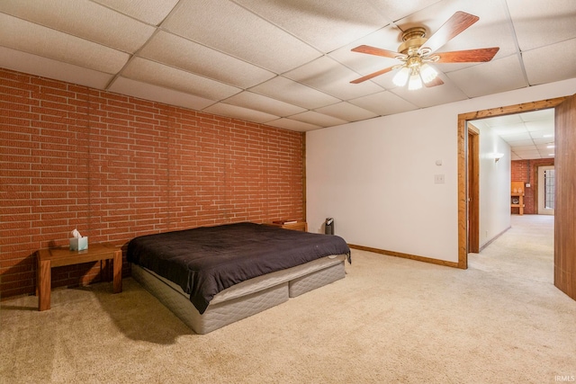 carpeted bedroom with brick wall, ceiling fan, and a paneled ceiling