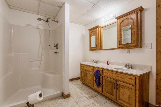 bathroom featuring tile floors, double sink vanity, a drop ceiling, and walk in shower