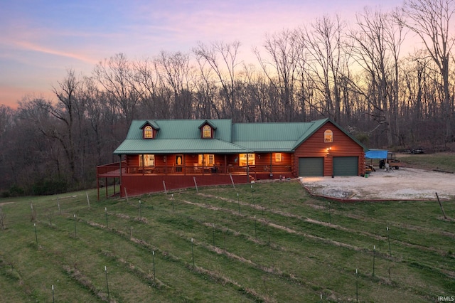 log home featuring a lawn, covered porch, and a garage