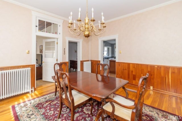 dining area with a notable chandelier, ornamental molding, light hardwood / wood-style floors, and radiator heating unit